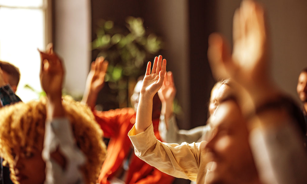 People with their hands raised, attending a conference.
