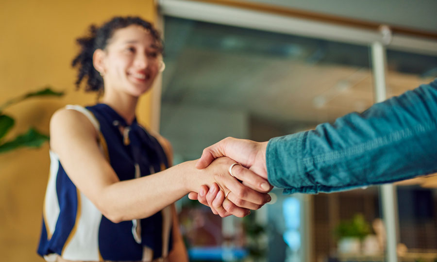 Young woman shaking hands with a new coworker after being hired.