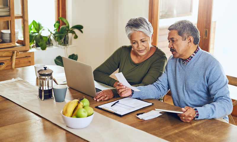 Retired couple sitting at their dining room table, going through their retirement info