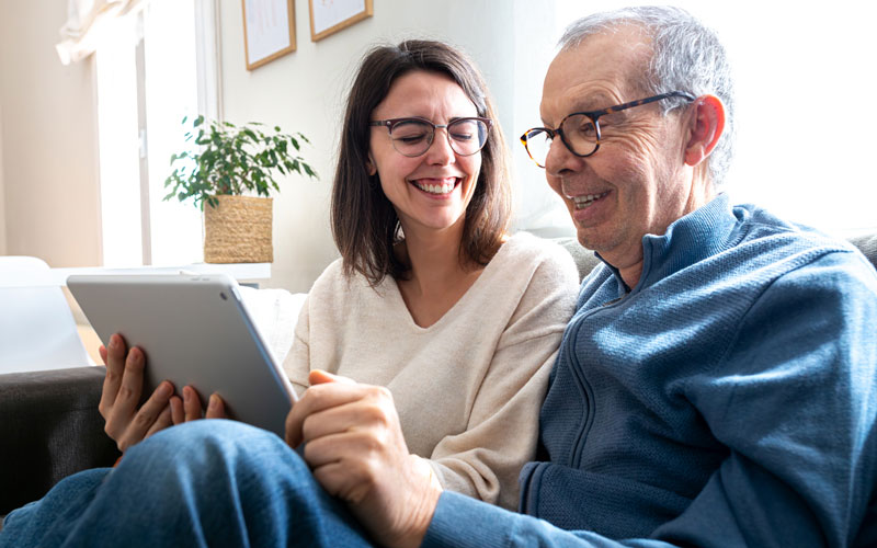 Middle aged daughter, laughing with father on the couch