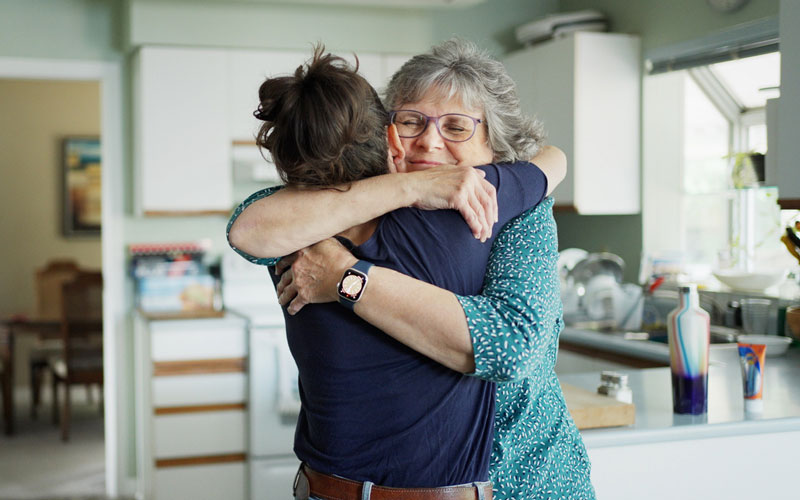 Middle aged daugther, hugging her mother in the Kitchen.