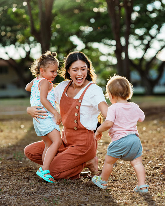 A young mother outside playing with her two daughters.